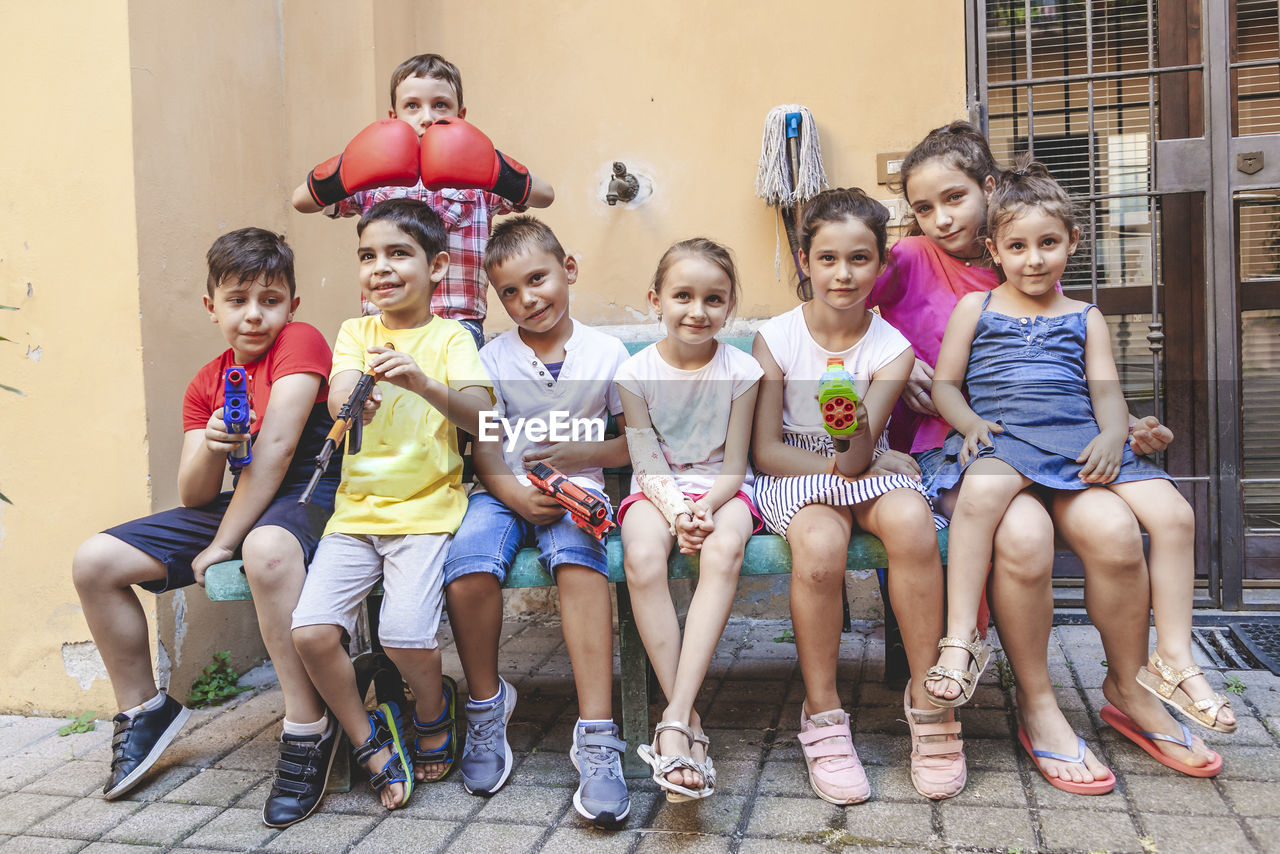 Group of little boys of different ages sitting having fun and playing together in a courtyard