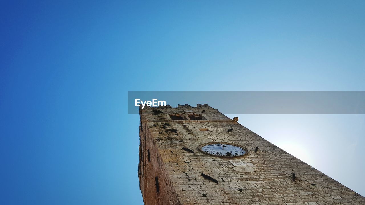 Low angle view of old tower against clear blue sky