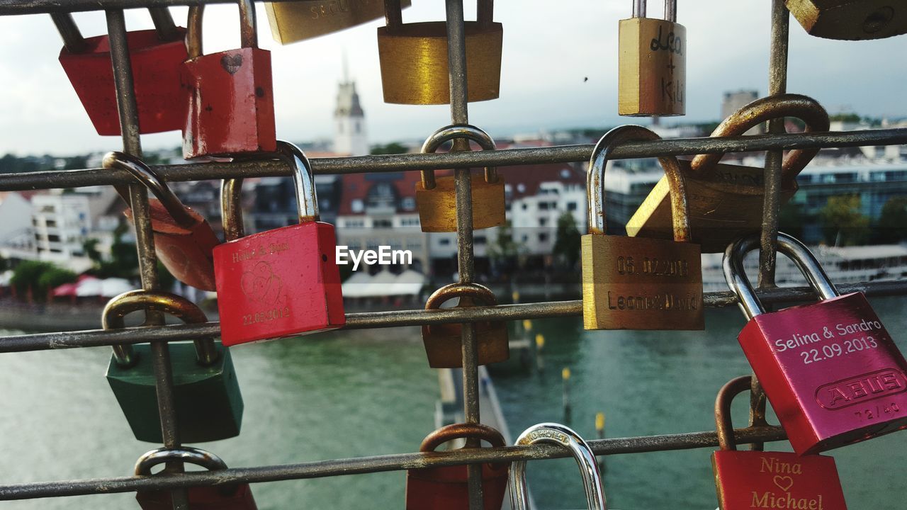 CLOSE-UP OF PADLOCKS HANGING ON RAILING AGAINST BLURRED BACKGROUND