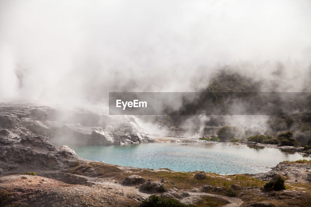 Scenic view of hot spring against cloudy sky