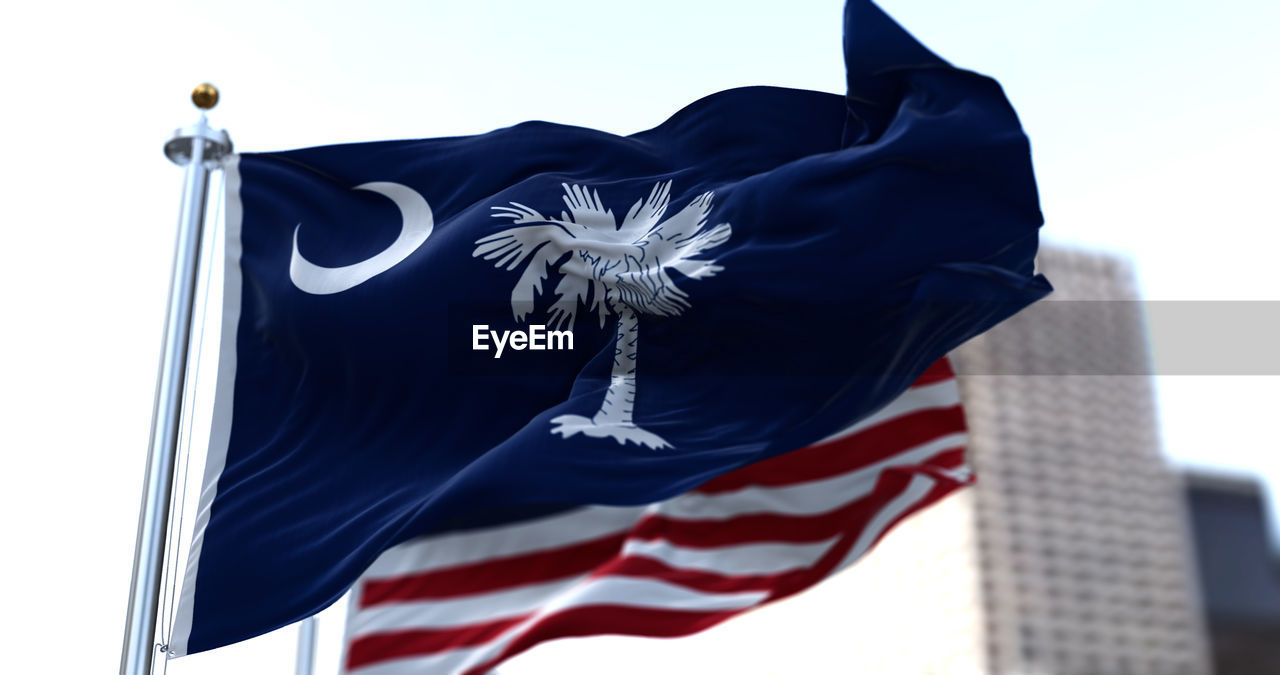 The flags of the south carolina state and united states of america waving in the wind. 