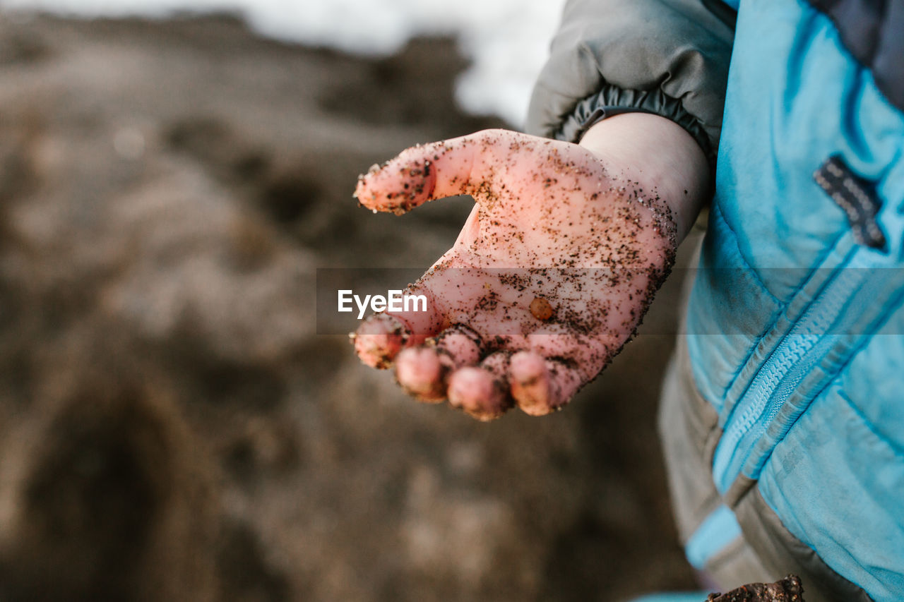 Close-up of messy hand with sand