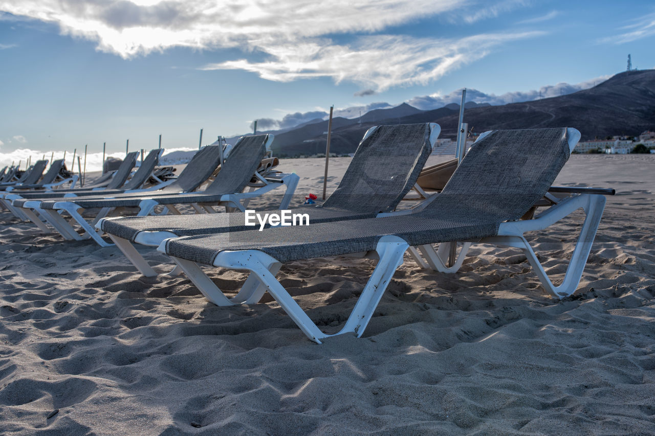 Chairs on beach against sky