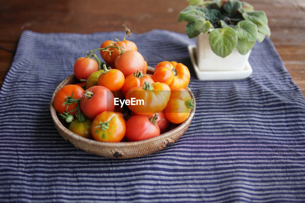 Fresh raw red tomatoes in basket on table