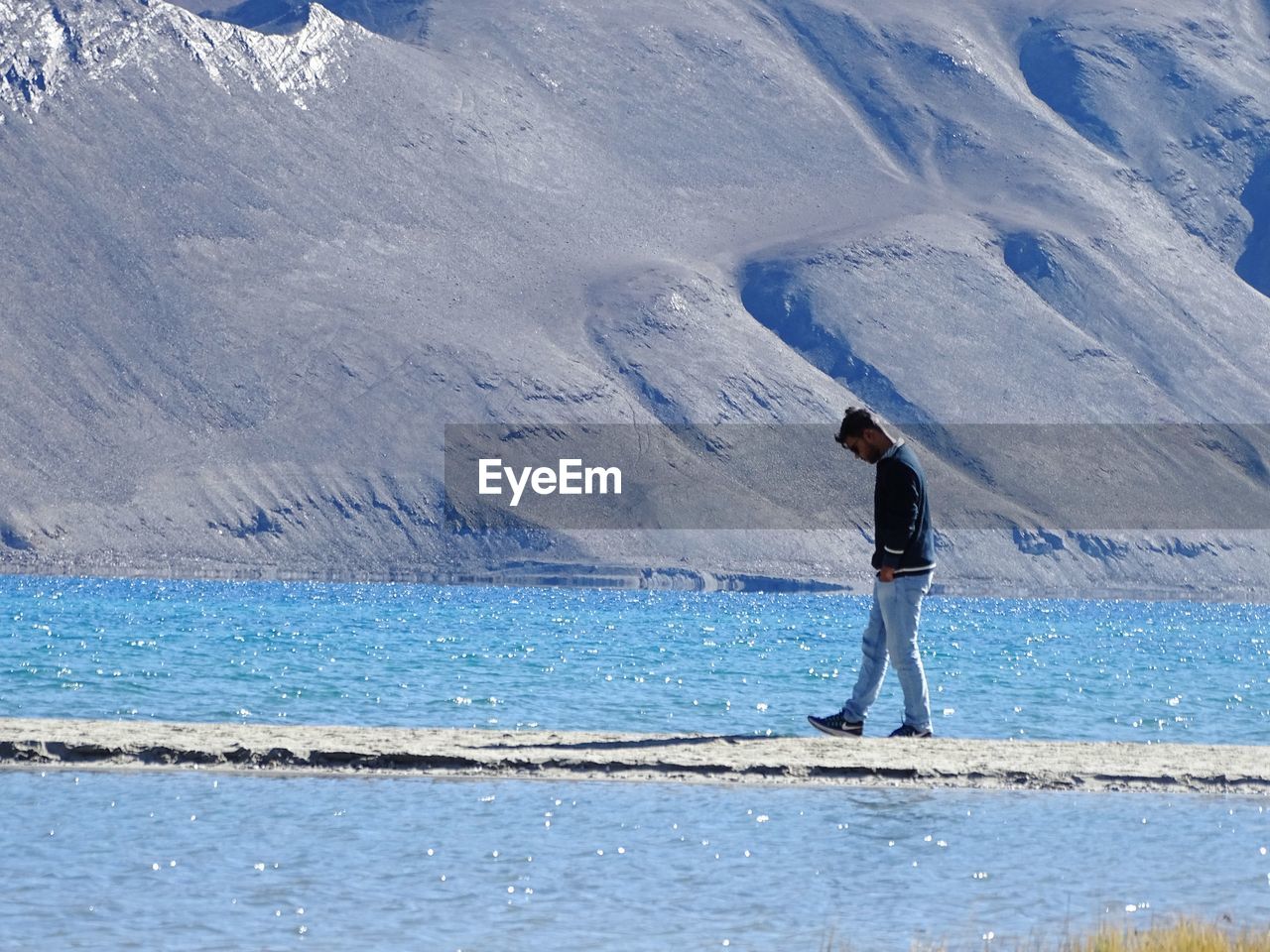 MAN STANDING ON SNOWCAPPED MOUNTAIN