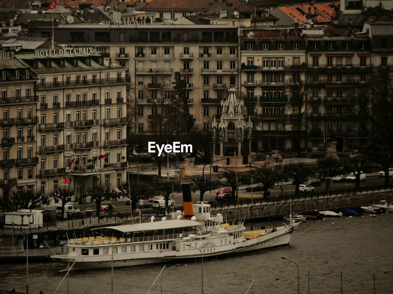 SAILBOATS MOORED IN HARBOR BY BUILDINGS IN CITY