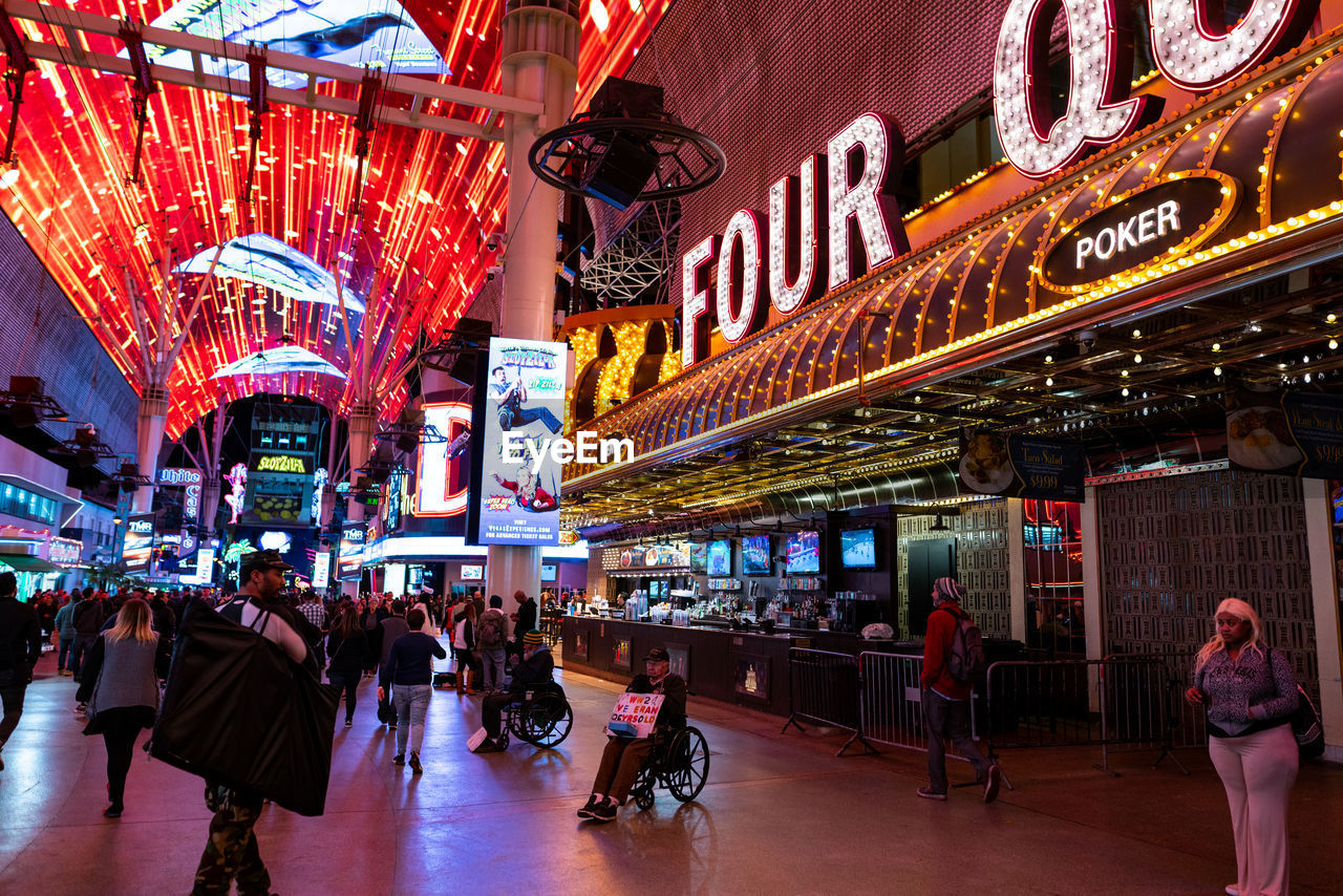 GROUP OF PEOPLE IN FRONT OF ILLUMINATED BUILDING AT NIGHT