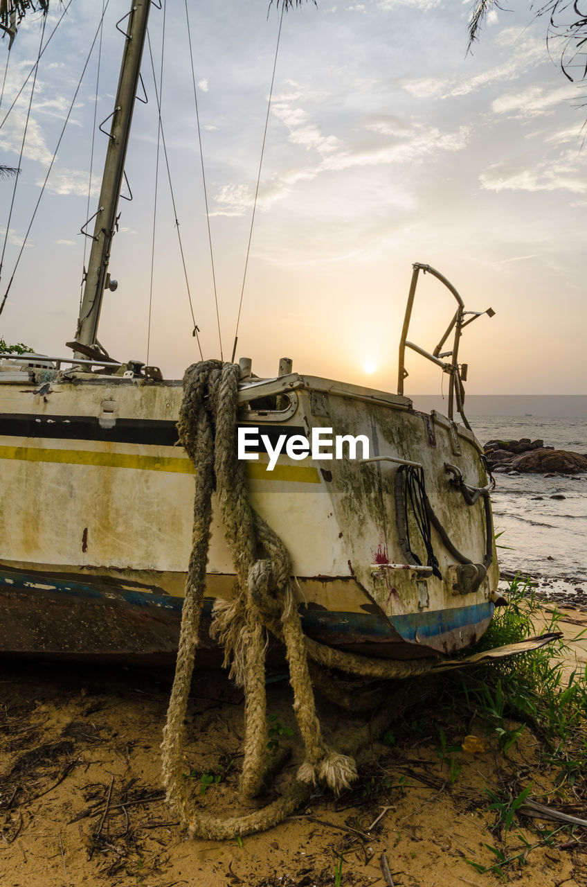 Abandoned boat stranded on beach against sky during sunset, kribi, cameroon