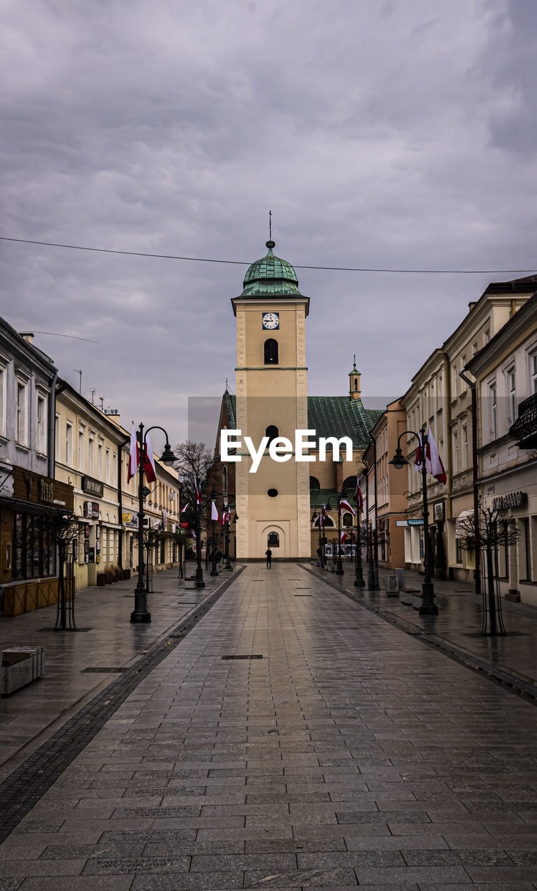 VIEW OF STREET AMIDST BUILDINGS AGAINST SKY