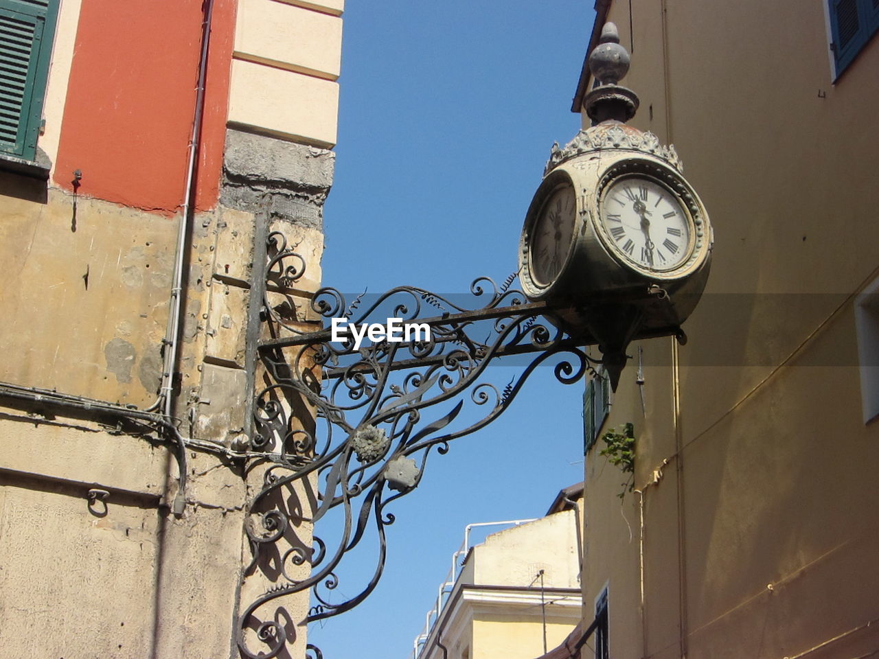 Low angle view of antique clock amidst buildings