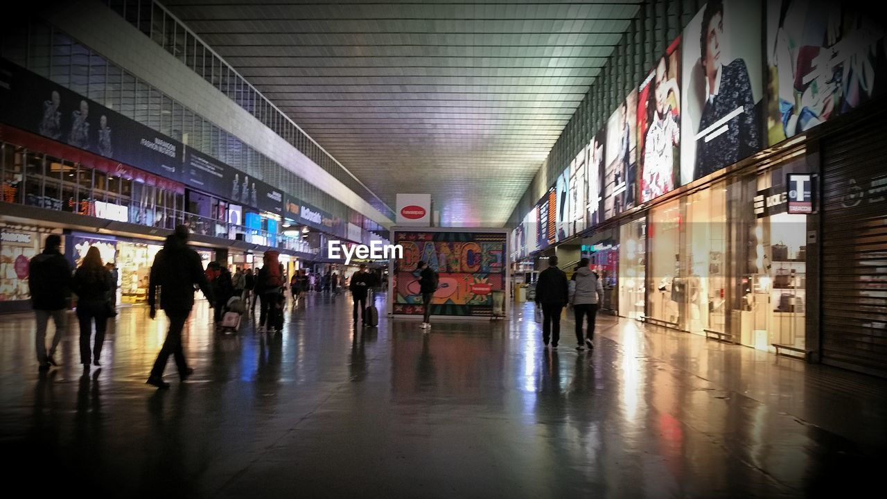 PEOPLE WALKING ON ILLUMINATED BUILDING