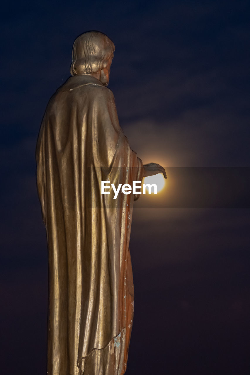 LOW ANGLE VIEW OF BUDDHA STATUE AGAINST SKY DURING SUNSET