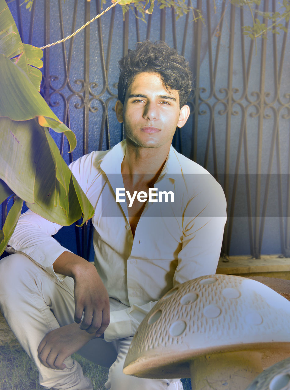 Portrait of young man crouching by artificial mushroom