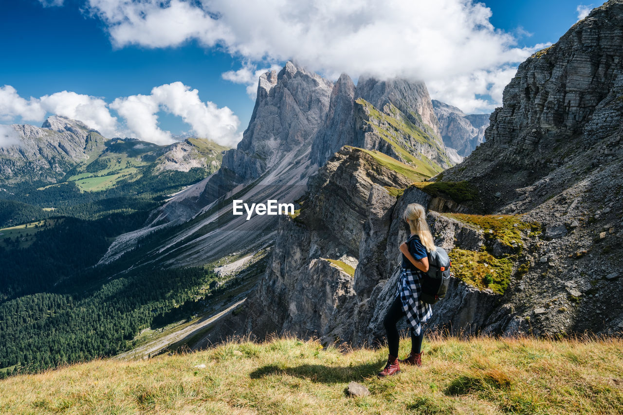 WOMAN STANDING ON MOUNTAIN AGAINST SKY