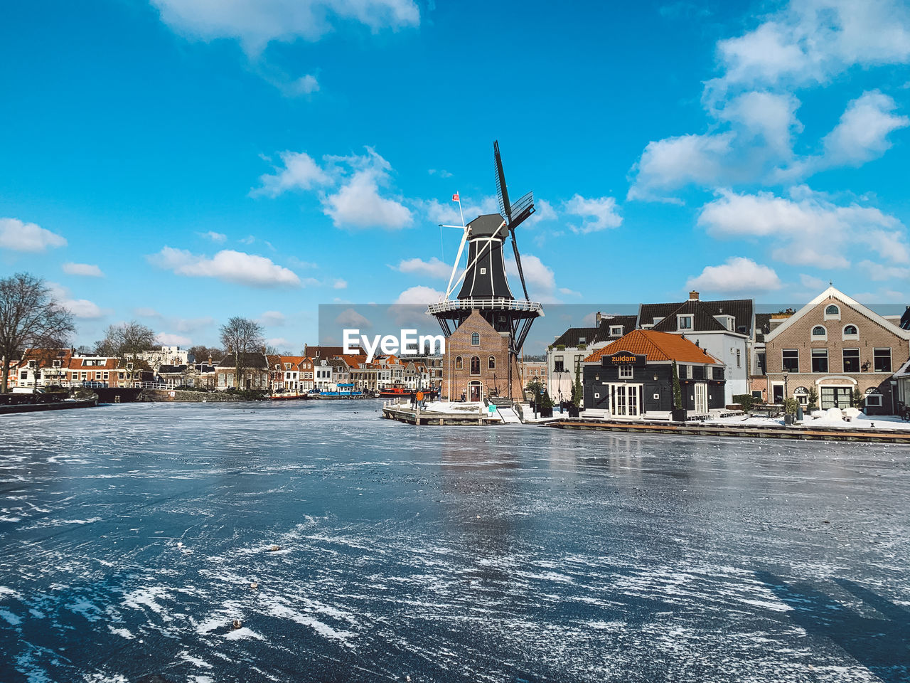 Windmill and buildings against blue sky