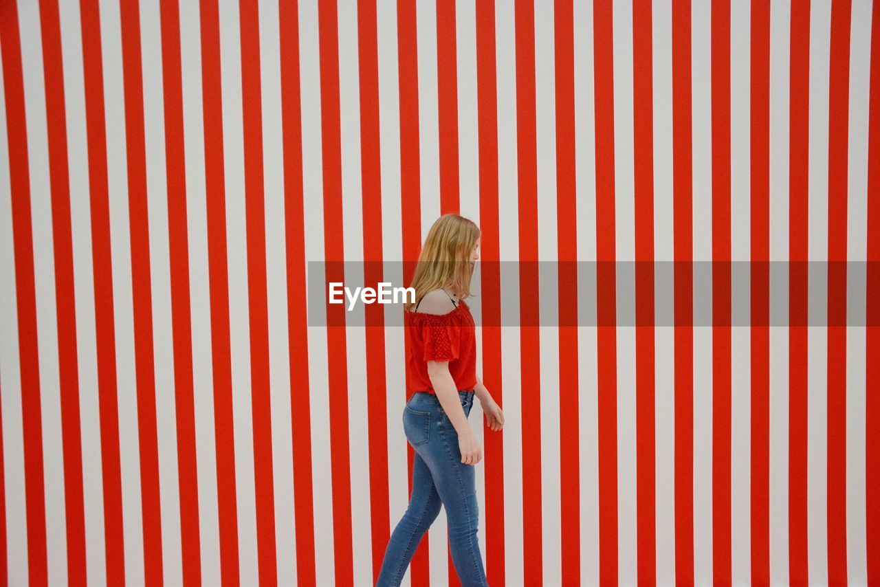 Girl walking by red striped wall