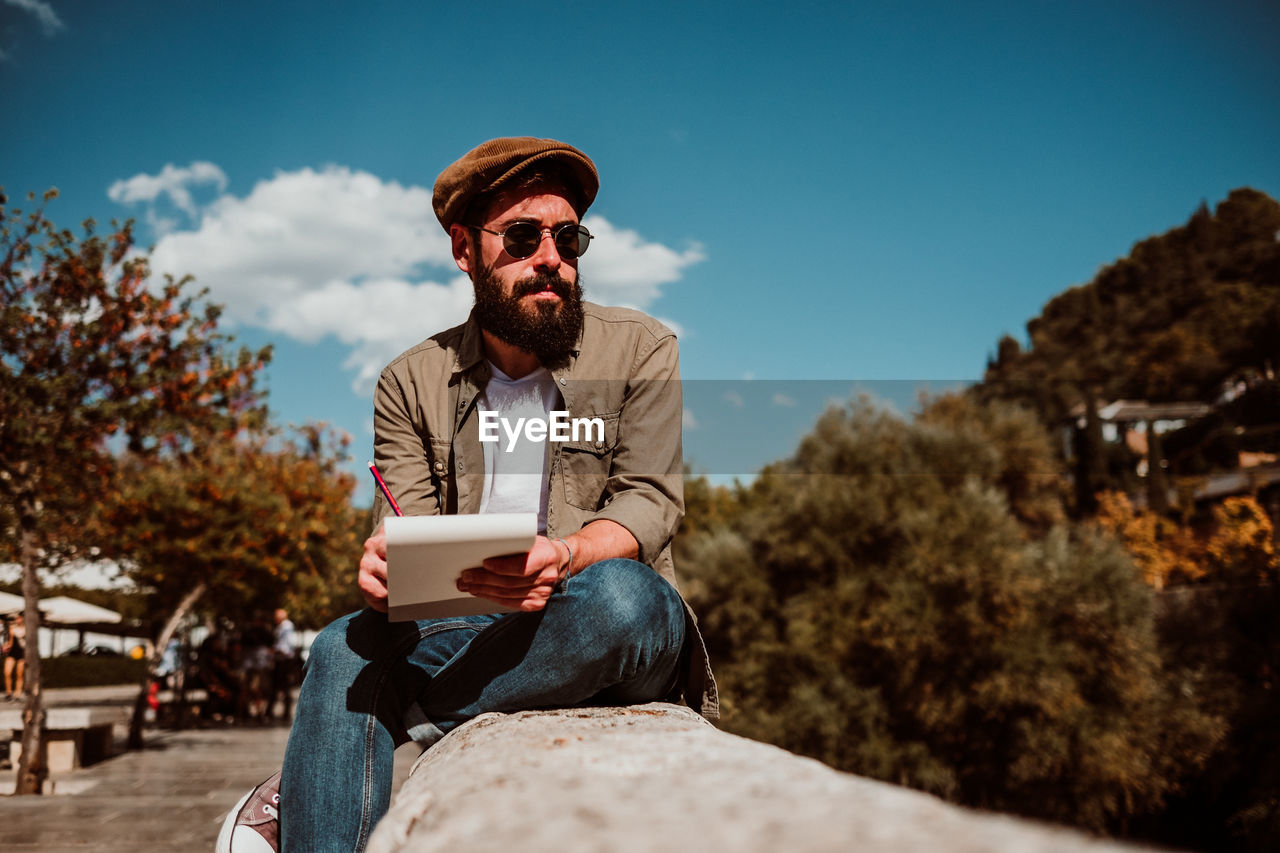 Man writing in book while sitting outdoors