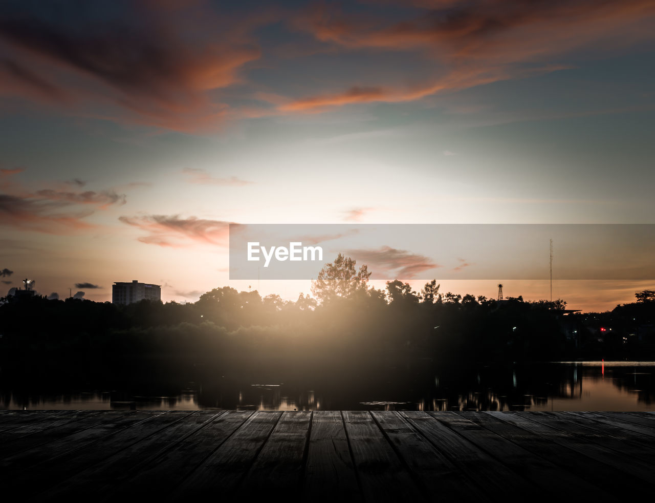 Scenery of wooden pier with dramatic sky sunrise above the pond