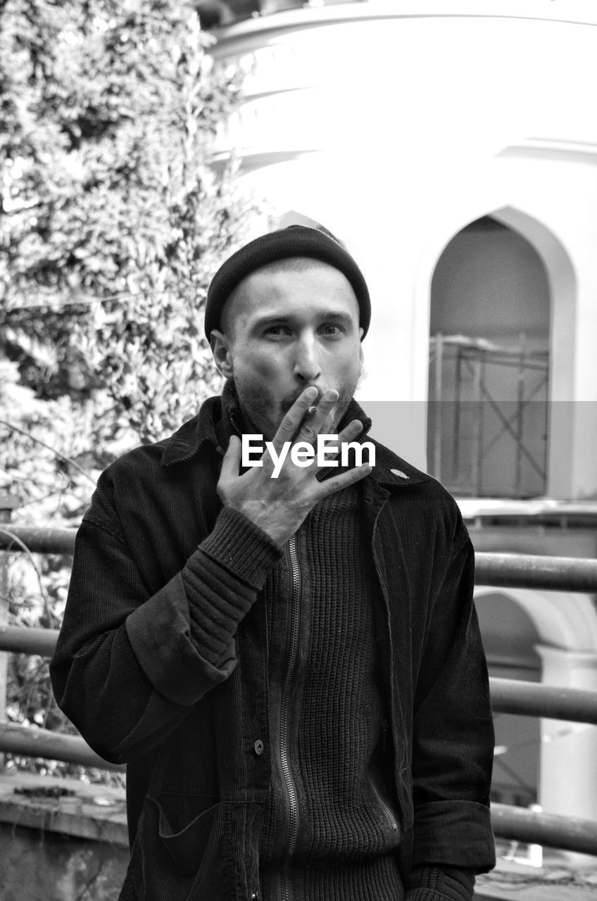 Portrait of man smoking cigarette in city