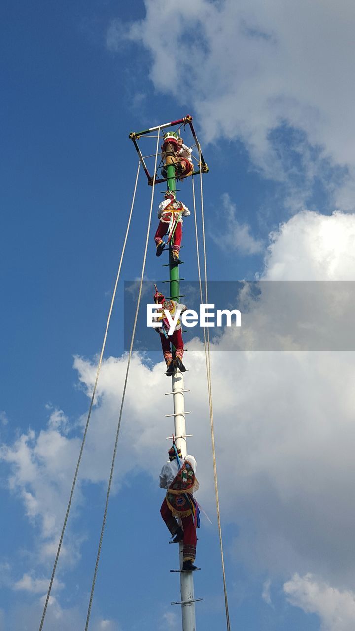 Low angle view of papantla flyers performing against sky