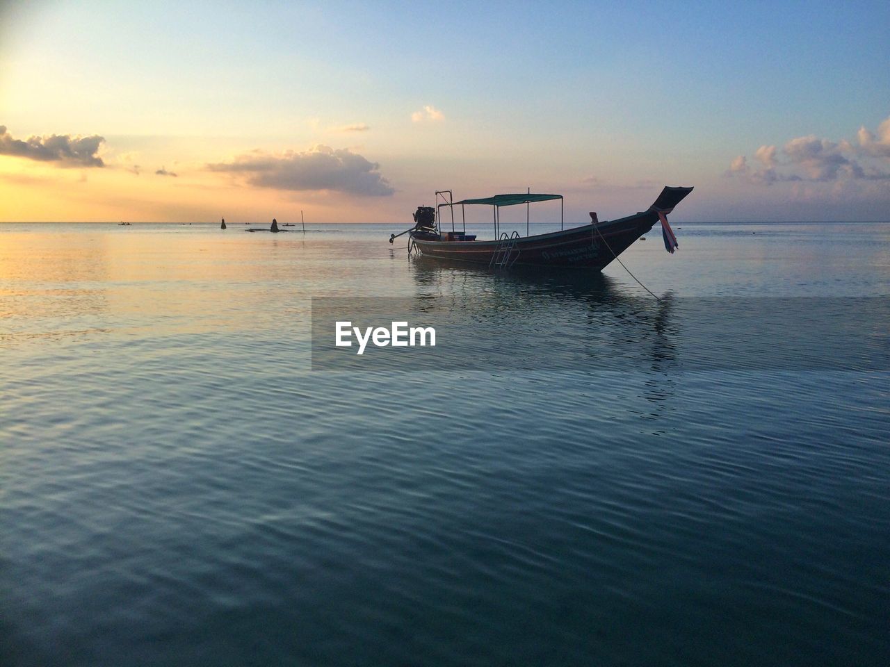 Longtail boat in sea against sky