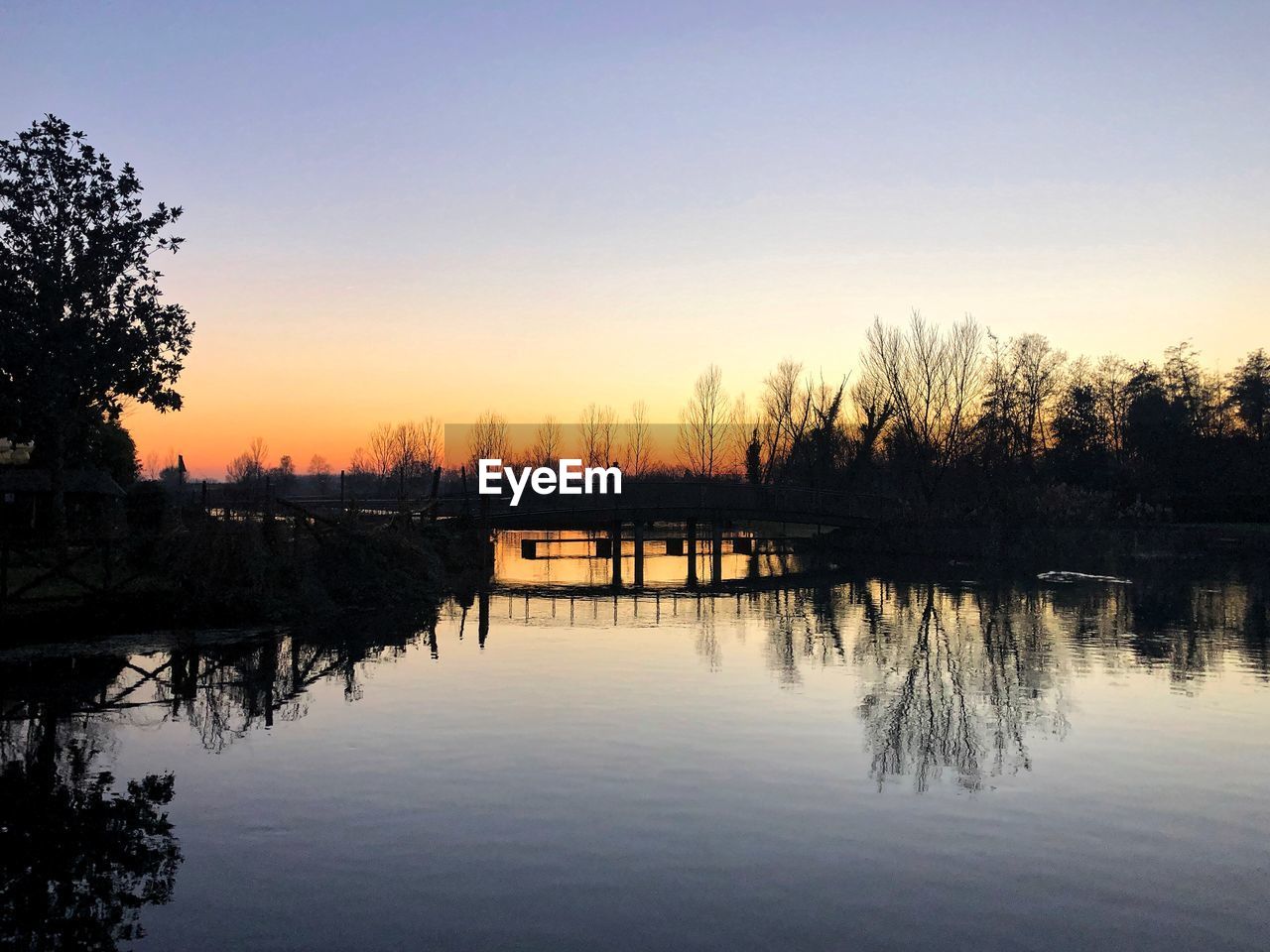 Scenic view of lake against clear sky during sunset