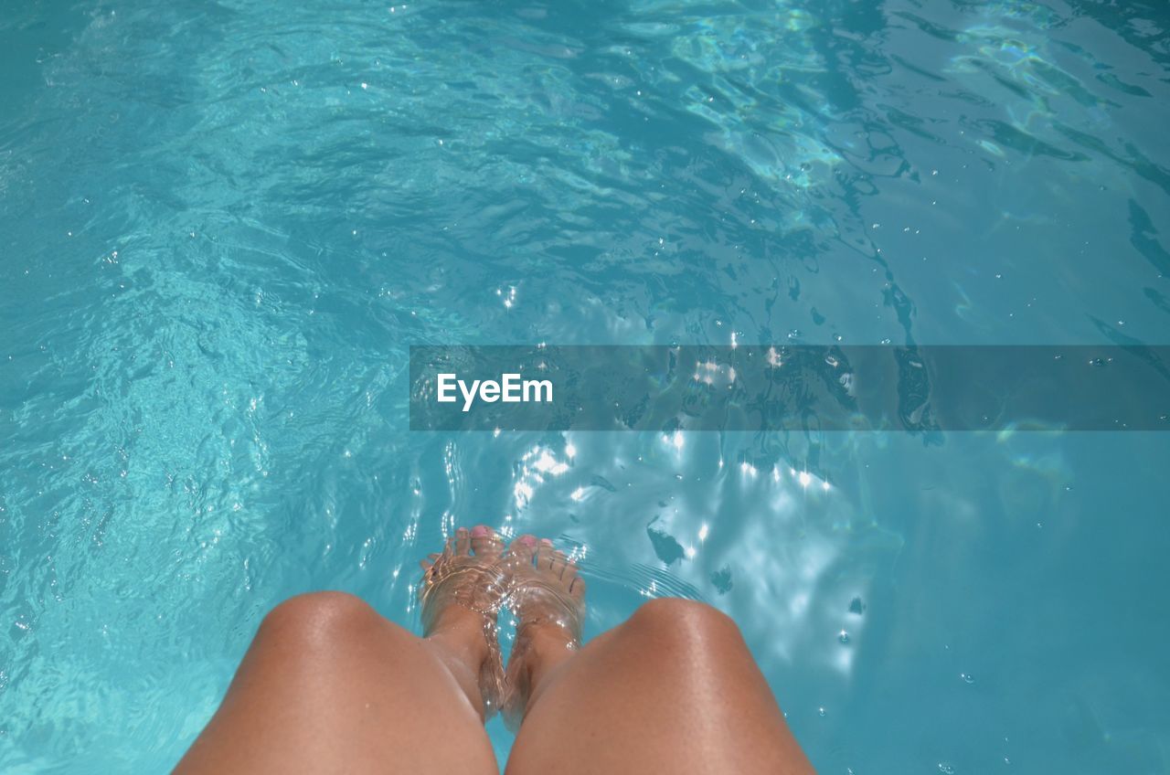 LOW SECTION OF WOMAN IN SWIMMING POOL