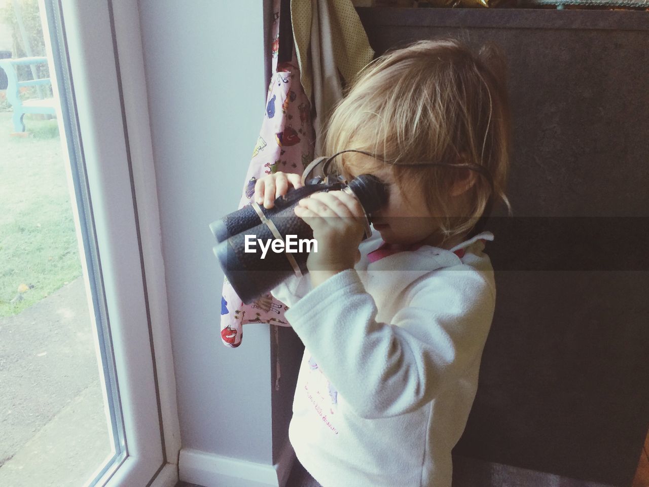 A toddler looking through binoculars 