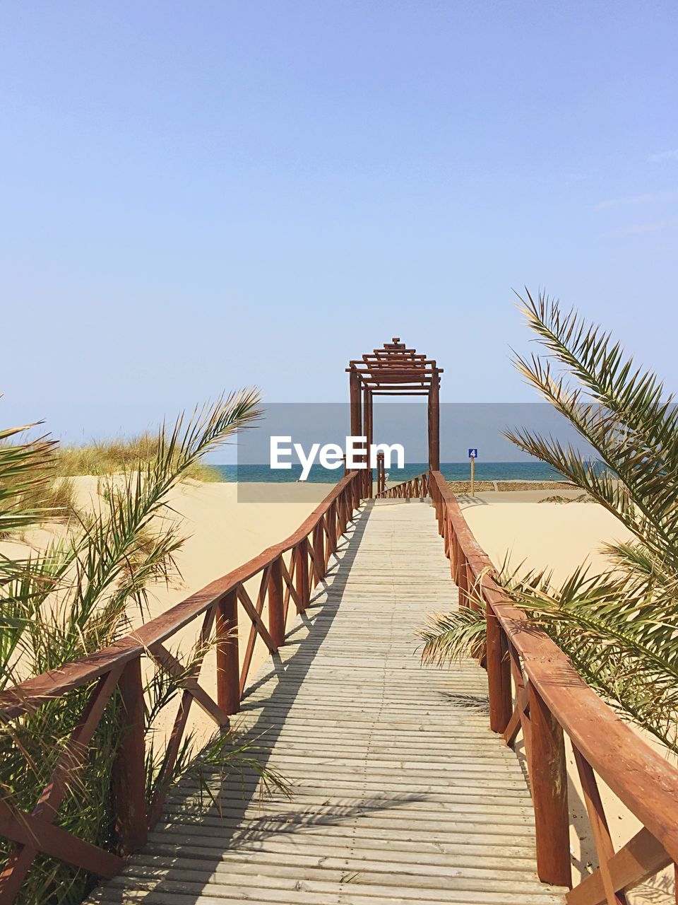 Pier over sea against clear blue sky