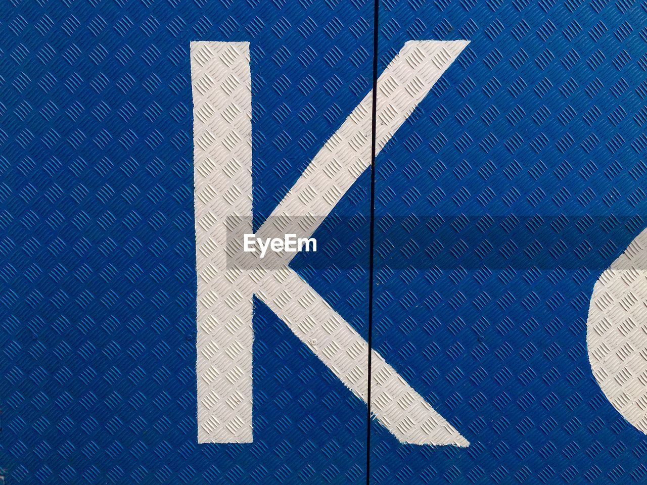 Close-up of alphabet k on blue diamond plate