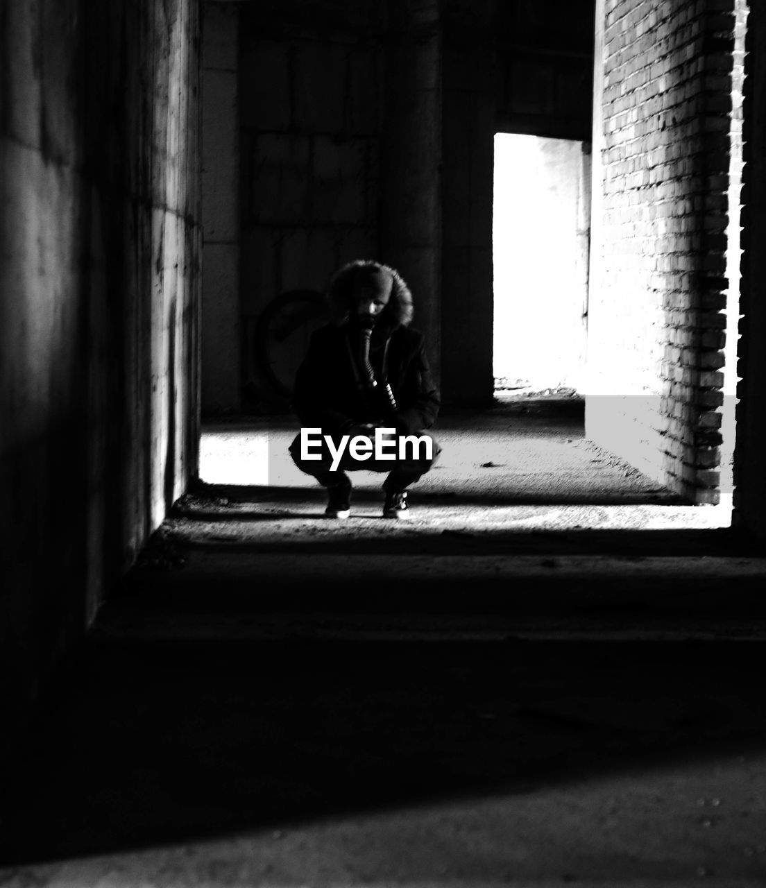 Full length of man crouching in abandoned building