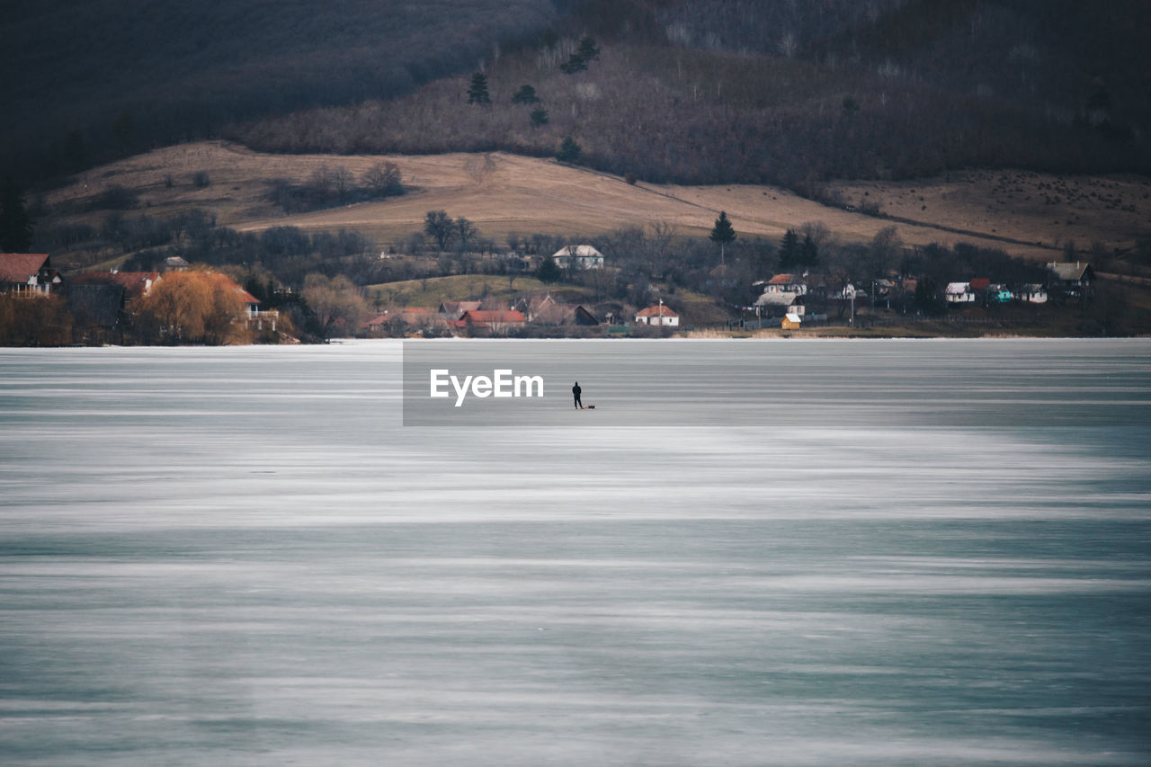 Distant view of person standing on frozen lake