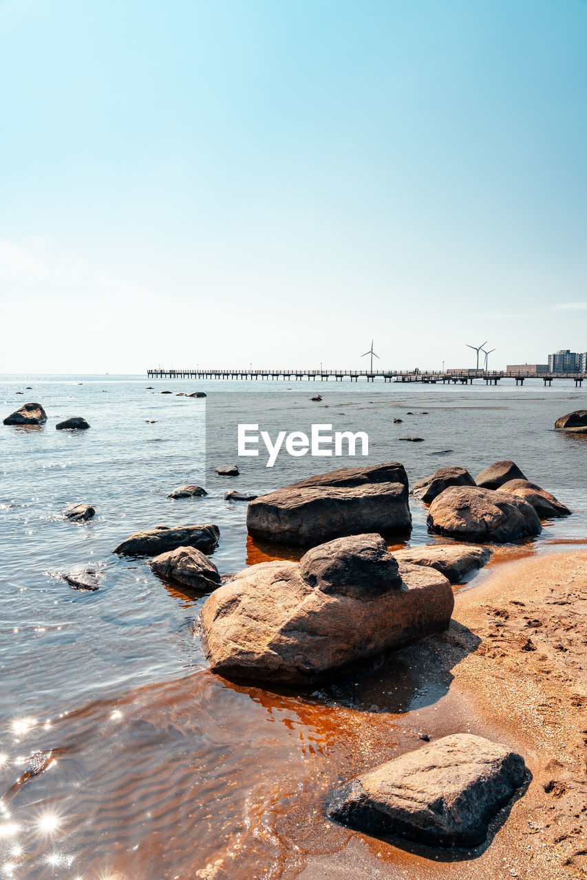 ROCKS ON SHORE AGAINST CLEAR SKY