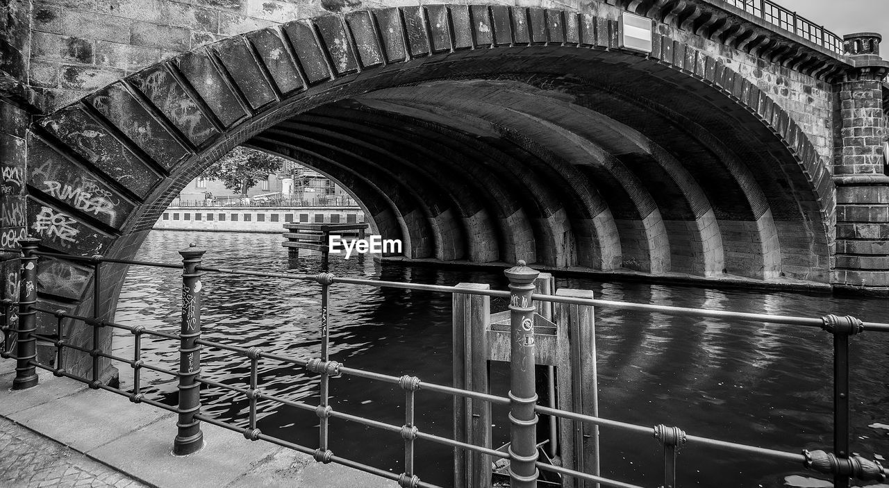 Arch bridge over river against building