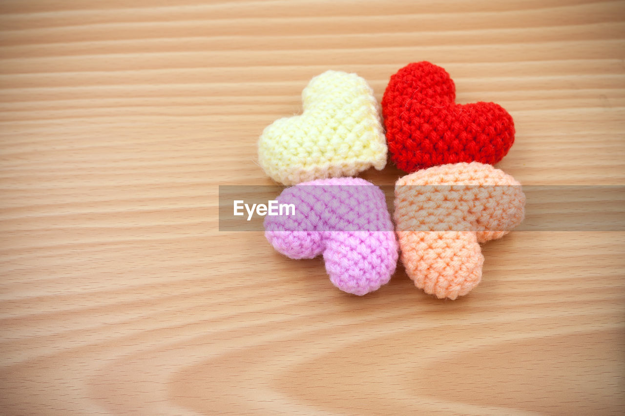 High angle view of multi colored woolen heart shapes on wooden table