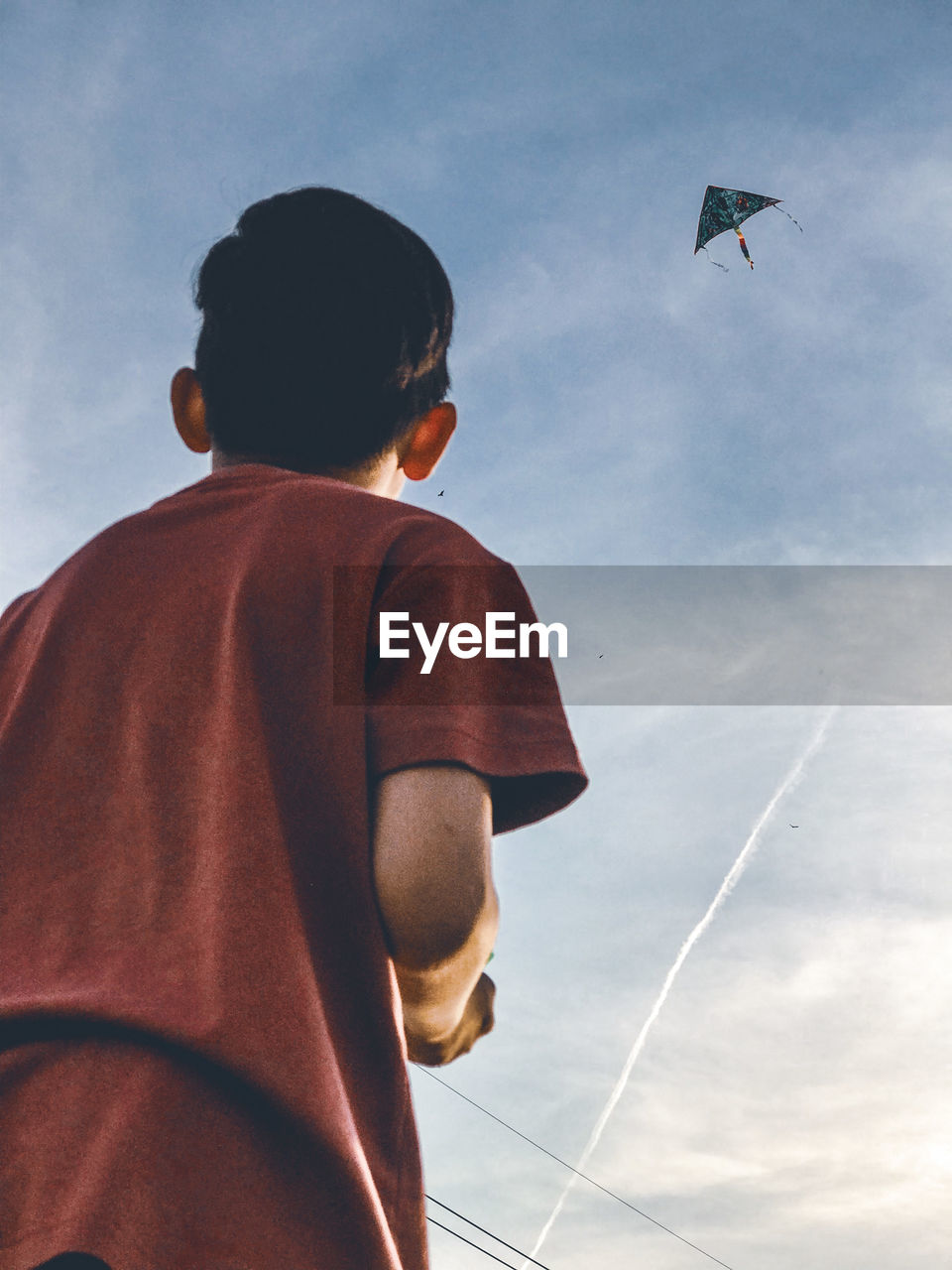 Side view of boy standing against sky