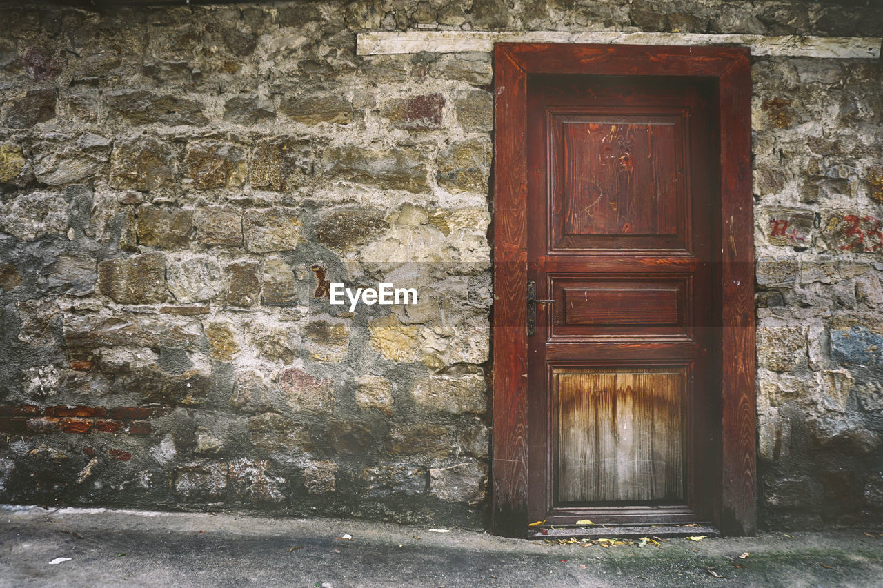 Closed wooden door on old stone wall building