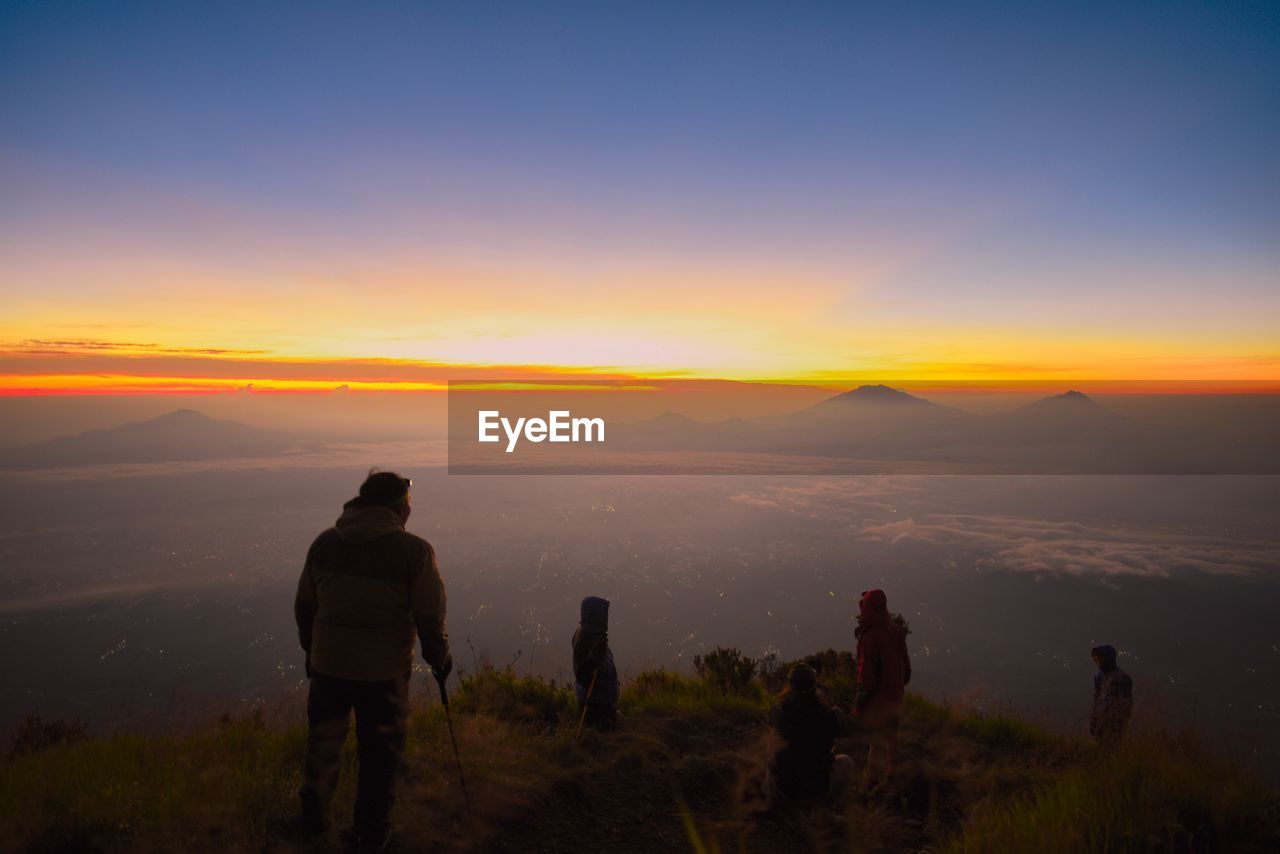People on mountain against sky during sunset
