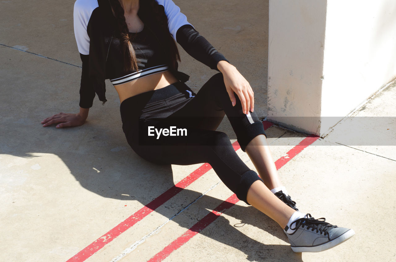 Low section of woman sitting on floor by wall