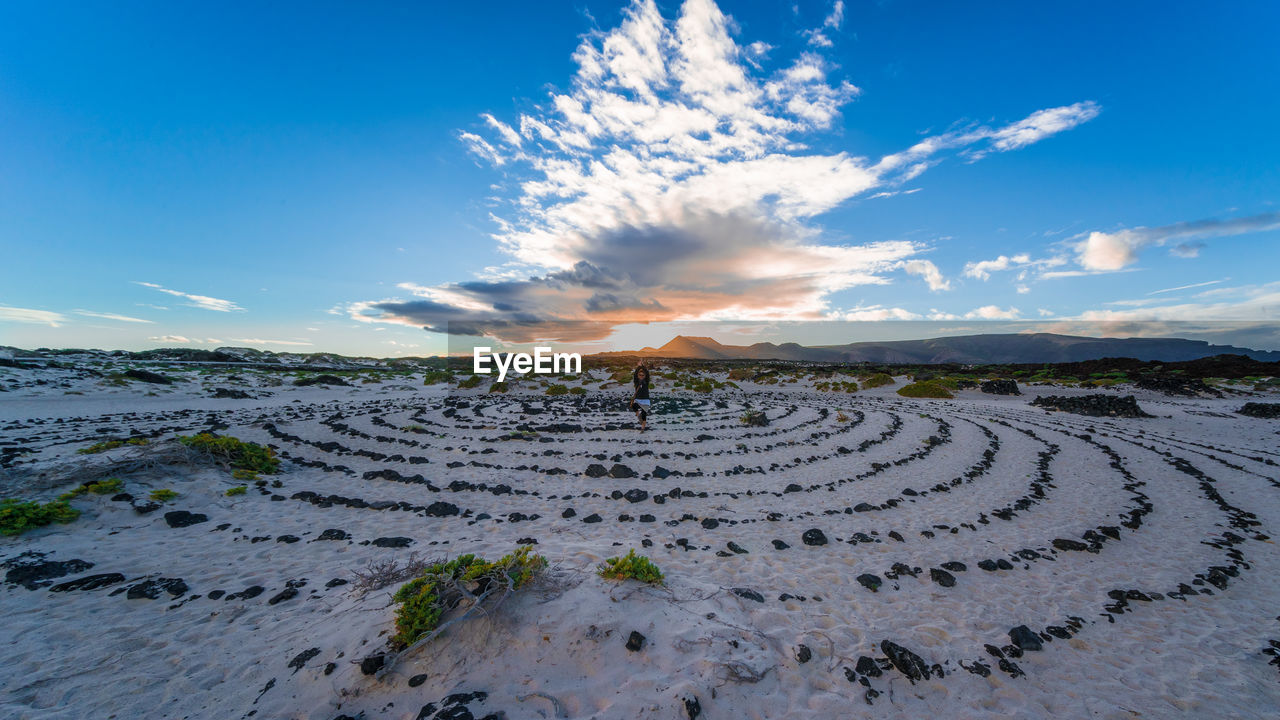 Woman sitting on landscape against sky