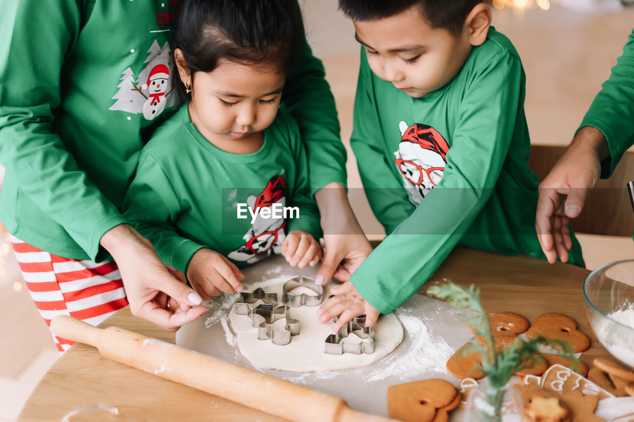 Asian family with two children in pajamas prepare festive food for the christmas holiday at home