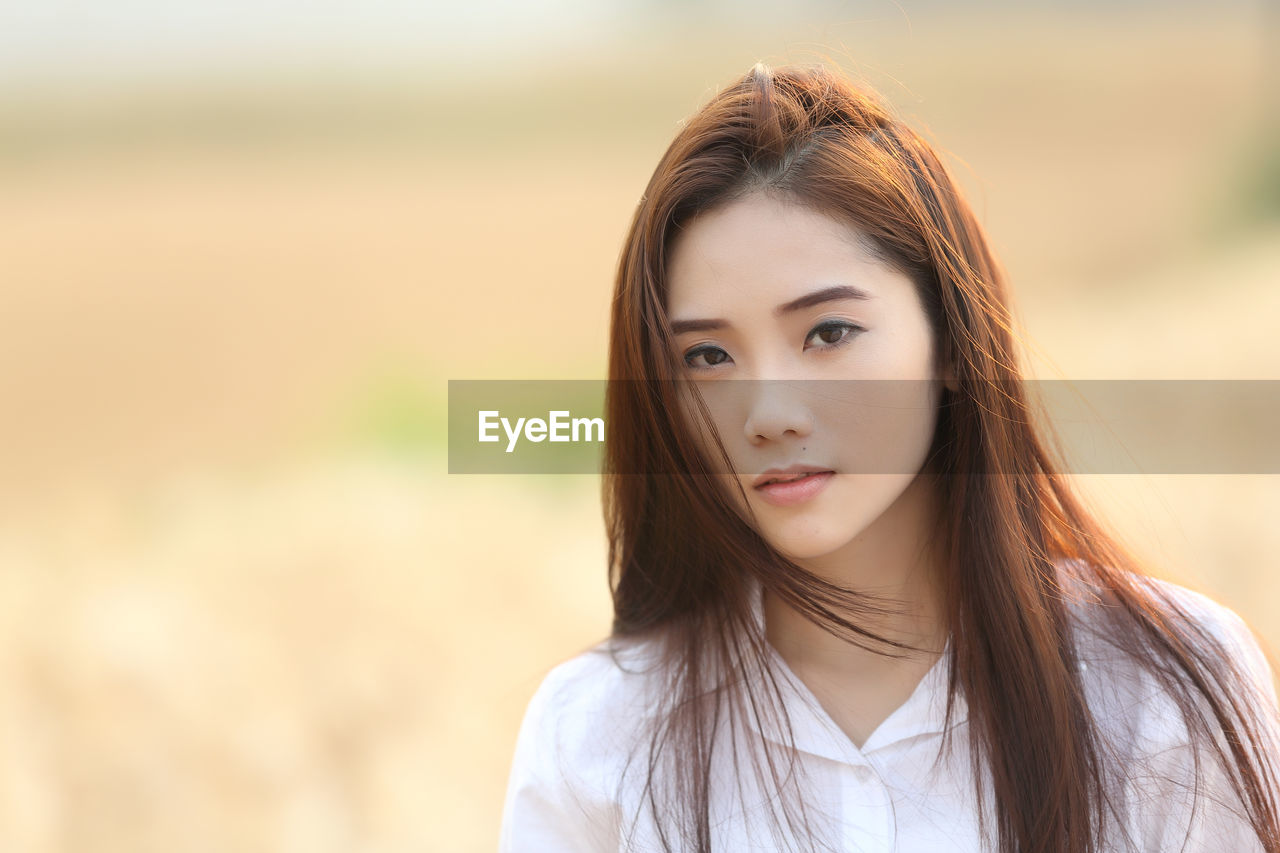 Portrait of beautiful young woman standing on field