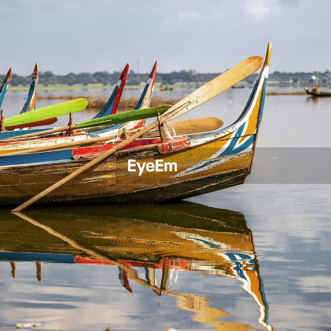 BOAT MOORED IN LAKE AGAINST SKY