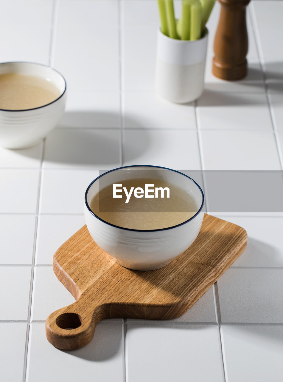 Homemade bone broth in a white bowl on a wooden board. the concept of a healthy diet.