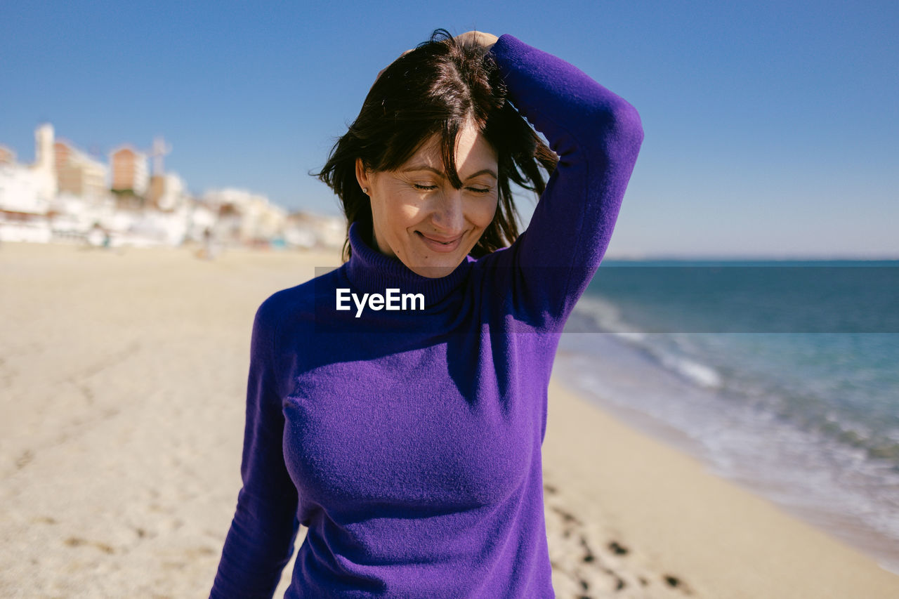 Beautiful happy mature woman enjoying a sunny winter day at the beach