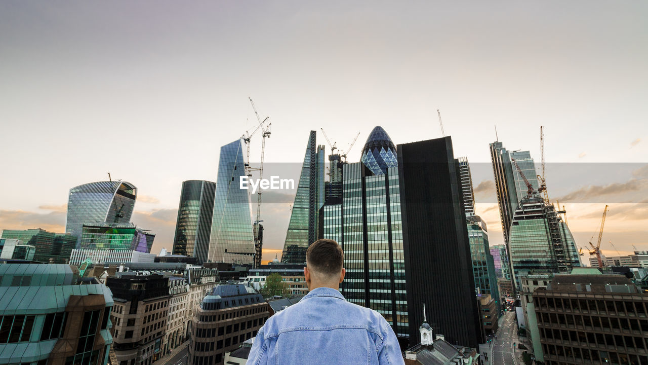 Rear view of man and buildings against sky