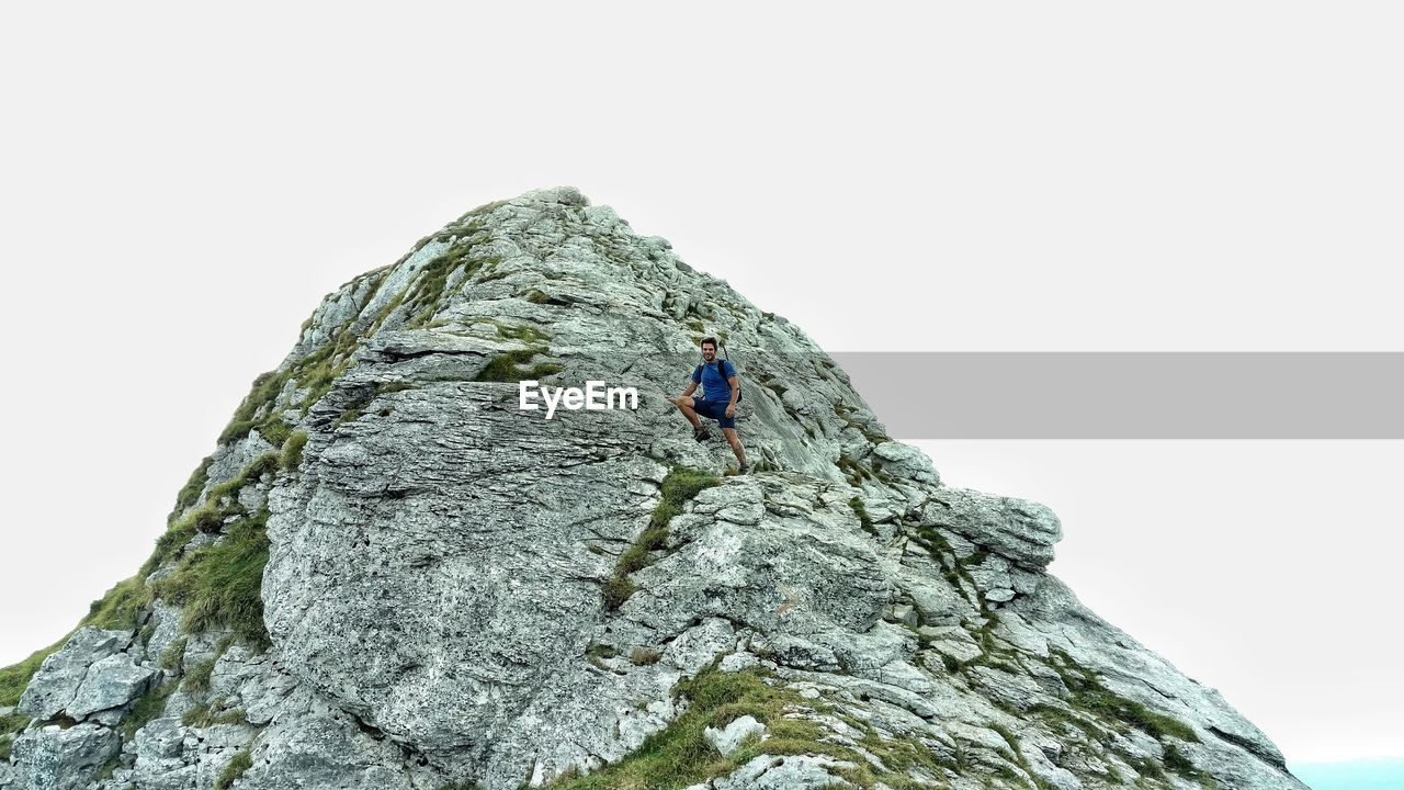 Low angle view of man standing on rock formation against sky