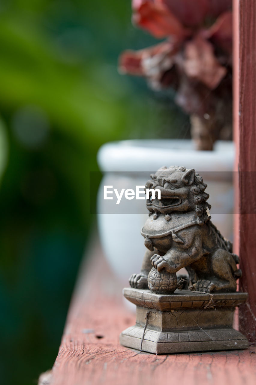 CLOSE-UP OF STATUE AGAINST TREE TRUNK