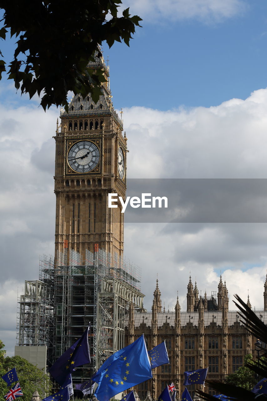 LOW ANGLE VIEW OF CLOCK TOWER AMIDST BUILDINGS AGAINST SKY