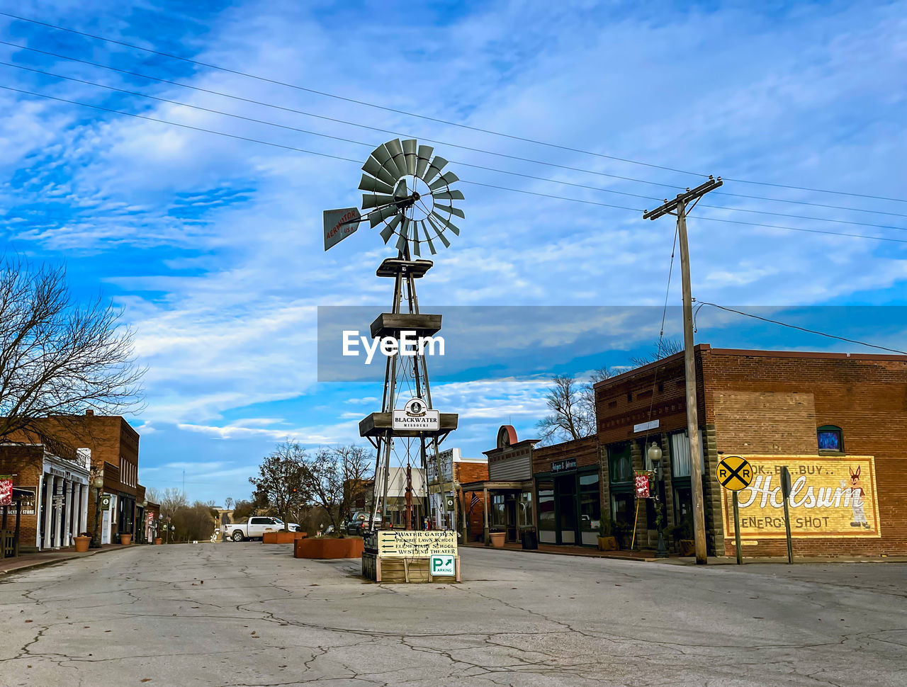 sky, architecture, built structure, power generation, town, nature, windmill, cloud, urban area, building exterior, city, street, day, building, renewable energy, environmental conservation, no people, outdoors, travel destinations, alternative energy, blue, tree, environment, technology, landmark, transportation, road, landscape